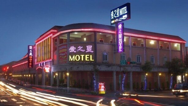 A motel with neon signage, a curved facade, and a street view with light trails. - Love Star Motel (Taoyuan City)