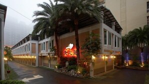 A hotel with a modern facade, palm trees, and a prominent illuminated sign. - Love Star Motel (Taoyuan City)