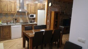 Une cuisine dotée de meubles en bois, d’un four à micro-ondes, d’un lave-vaisselle et d’un coin repas avec une table et des chaises.