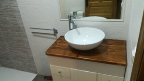 Une salle de bain avec un lavabo blanc posé sur un plan de travail en bois, un porte-serviettes et un miroir au-dessus du lavabo.