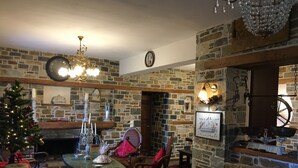 Ein gemütliches Wohnzimmer mit Kamin aus Stein, einer hölzernen Bank, einem Esstisch mit einer Chandelier und einem Weihnachtsbaum.