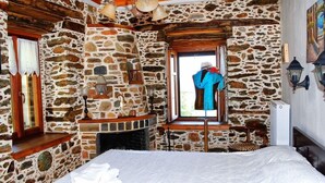Ein Schlafzimmer mit Stehwänden, einem Bett, einem Fenster und einem Kamin.
