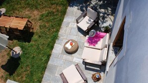 Eine Terrasse mit Gartenmöbeln, einem kleinen runden Tisch und einem Stuhl.