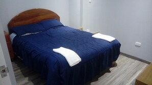 A bed with a wooden headboard, a blue bedspread, and white pillows. - THE HOUSE OF JOSE Second Floor  (Cuzco)