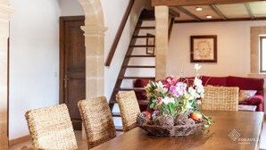 A dining area with a wooden table, wicker chairs, and a centerpiece of flowers and pinecones.