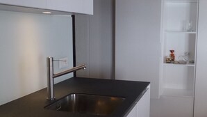 A modern kitchen with a stainless steel sink, a cutting board, and a knife.
