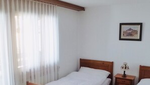 A single-bed room with a wooden headboard, a bedside table with a lamp, and a framed picture on the wall.