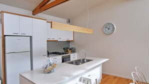 Una cuina moderna amb armaris blancs, un rentapeus d'acer inoxidable i un rellotge a la paret.