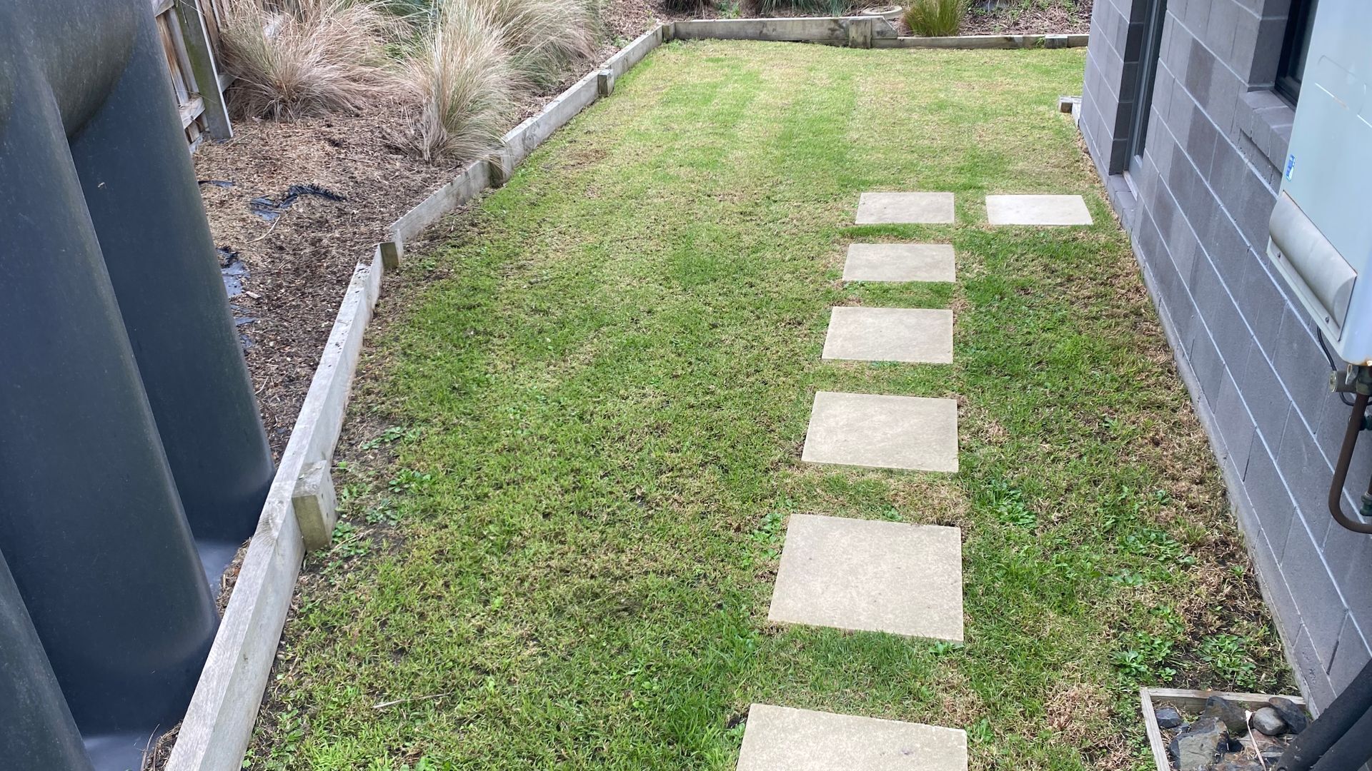 A pathway leading to a building with a well-maintained lawn and a concrete border.