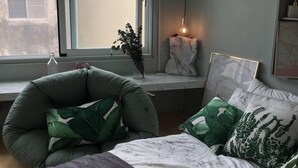 A bedroom with a bed, a chair, a window, and a bedside table with a lamp. - We2 AnPing Hostel (Tainan)