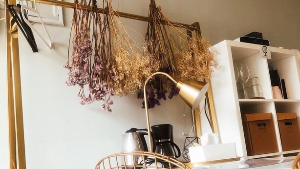 A modern room with a white desk, a gold chair, a hanging plant arrangement, and a coffee machine. - We2 AnPing Hostel (Tainan)