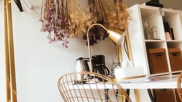 A modern room with a white desk, a gold chair, a hanging plant arrangement, and a coffee machine.