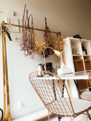 A modern room with a white desk, a gold chair, a hanging plant arrangement, and a coffee machine. - We2 AnPing Hostel (Tainan)