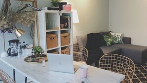 A modern living space with a white sofa, a coffee table with a laptop, a bookshelf, and a hanging plant. - We2 AnPing Hostel (Tainan)