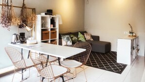A modern living space with a dining area, sofa, and storage units. - We2 AnPing Hostel (Tainan)