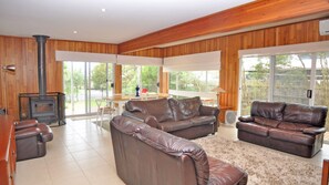 Un salón amplio con sofás de cuero, una chimenea y ventanas grandes con vistas al exterior.