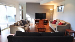 Ein Wohnzimmer mit zwei Sofas, einem Couchtisch, einer TV-Konsole und einer Stehlampe.