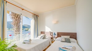 A hotel room with two beds, a view of the sea, and a balcony with curtains. - House mountain view Lago Miguel in Alcudia (Alcúdia)