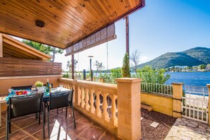 A terrace with a wooden ceiling, a table with chairs, and a view of a lake and mountains. - House mountain view Lago Miguel in Alcudia (Alcúdia)
