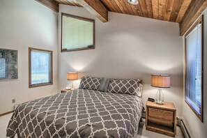 A bedroom with a large bed, two bedside lamps, and a nightstand with a lamp.