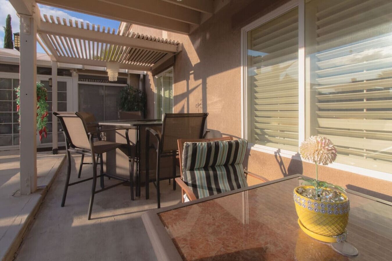 An outdoor patio with a table and chairs, a covered seating area, and a potted plant.