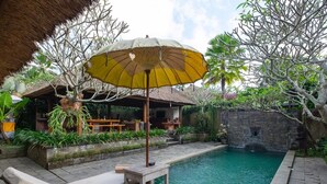 A poolside area with a lounge chair, a table, and an umbrella. - Ubud Serendipity Villa (Ubud)