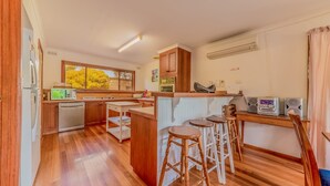 A modern kitchen with wooden cabinets, a built-in oven, and a large window. - Driftwood On Anderson - Free Wifi (INVERLOCH)