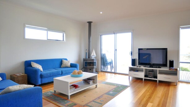 Una sala de estar con un sofá azul, una mesa de centro blanca, un televisor y una chimenea.