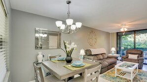A dining area with a table set for four, a chandelier, and a clock on the wall. - Bonita Springs Vacation Rental w/ Community Pool! (Bonita Springs)