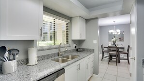 A modern kitchen with granite countertops, stainless steel sink, and white cabinetry. - Bonita Springs Vacation Rental w/ Community Pool! (Bonita Springs)