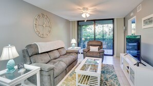 A living room with a sofa, armchair, coffee table, and a large wall clock. - Bonita Springs Vacation Rental w/ Community Pool! (Bonita Springs)