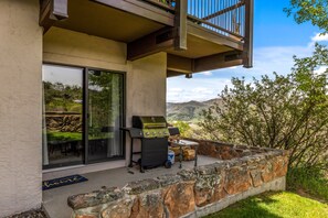 A patio with a grill, a stone wall, and a view of the landscape. - Storm Meadows C210 | Pool & Hot Tub | Colorful Design | Ski In Ski Out (Steamboat Springs)