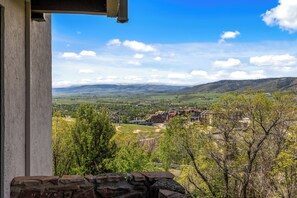 A view from a balcony overlooking a valley with buildings and mountains.