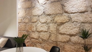 Una habitación con una pared de piedra, una mesa redonda y dos plantas en macetas.