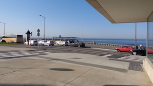 Un área de estacionamiento frente al mar con un autobús, coches y una pasarela para peatones.