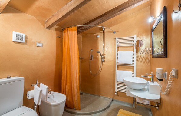 A bathroom with a toilet, bidet, sink, and shower.