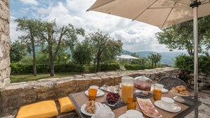 An outdoor dining area with a table set for breakfast, including eggs, fruit, and beverages, overlooking a scenic landscape. - Stunning private villa with A/C, hot tub, WIFI, private pool, TV, patio and panoramic view (Monsummano Terme)