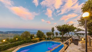 A rectangular pool with a wooden deck and a floating platform, surrounded by stone steps and trees. - Stunning private villa with A/C, hot tub, WIFI, private pool, TV, patio and panoramic view (Monsummano Terme)