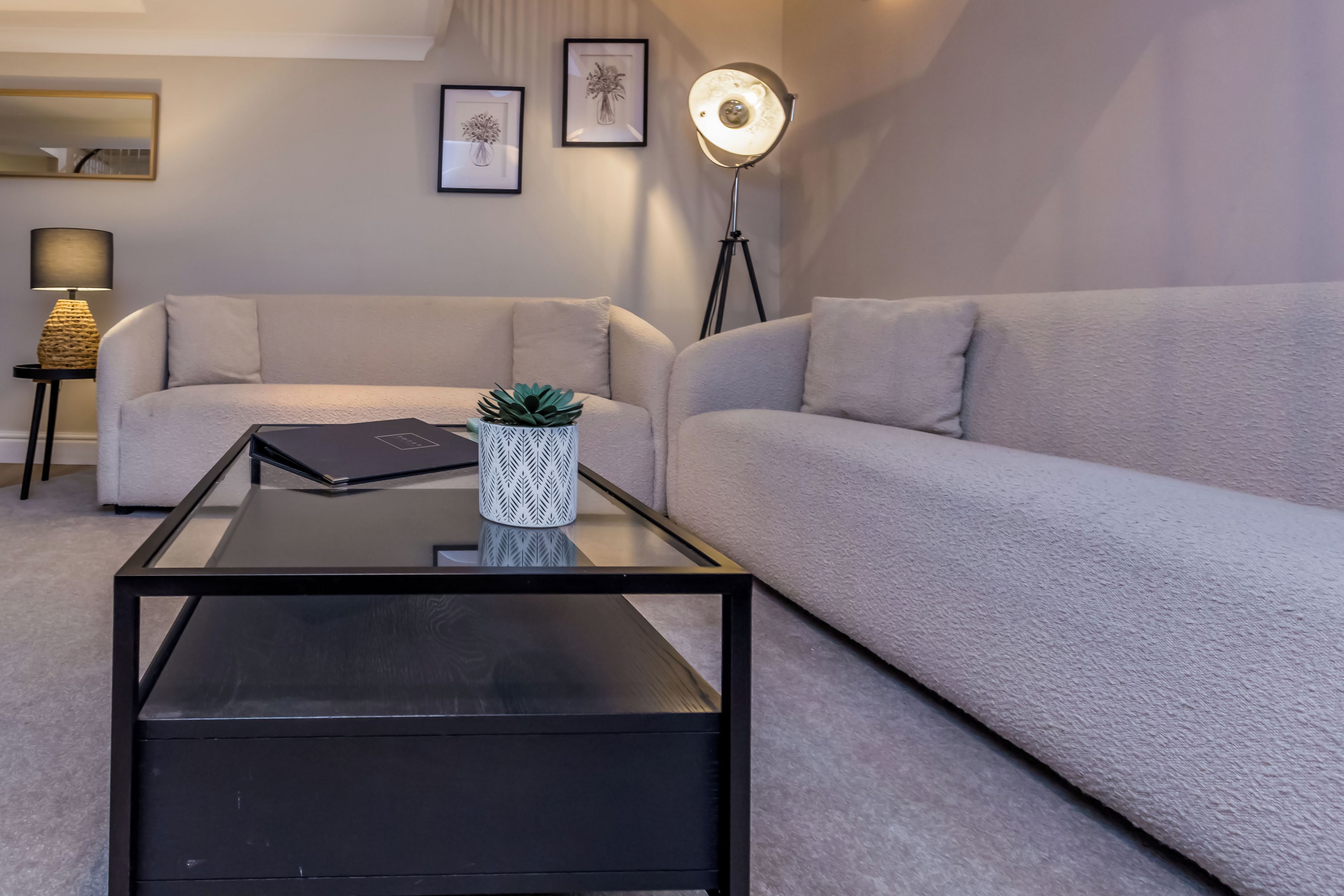Un salon moderne avec un canapé, une table basse, une lampe et un lampadaire.
