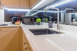 A modern kitchen with a white countertop, stainless steel appliances, and a built-in sink.