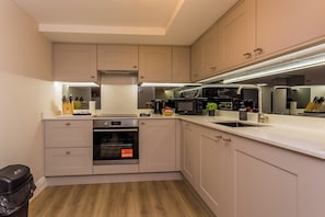 Une cuisine moderne dotée d’appareils électroménagers intégrés, d’un four en acier inoxydable et d’un four à micro-ondes.