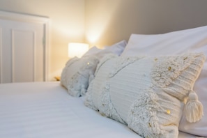 A neatly made bed with white bedding and decorative pillows.