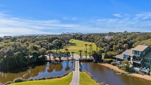 Un parcours de golf avec un plan d’eau, un pont et des immeubles résidentiels en arrière-plan.