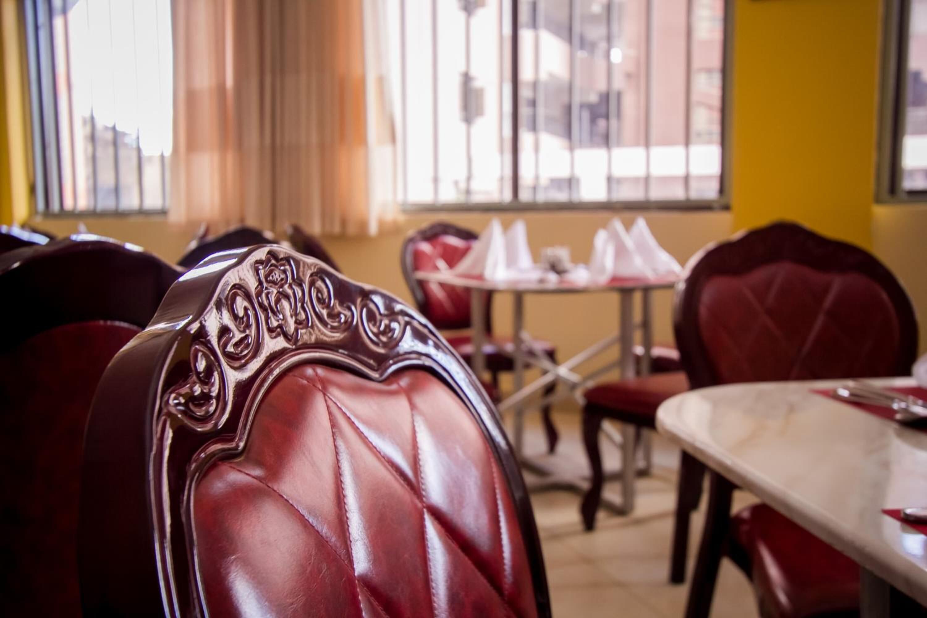Un comedor con sillas tapizadas en rojo y una mesa de mármol.