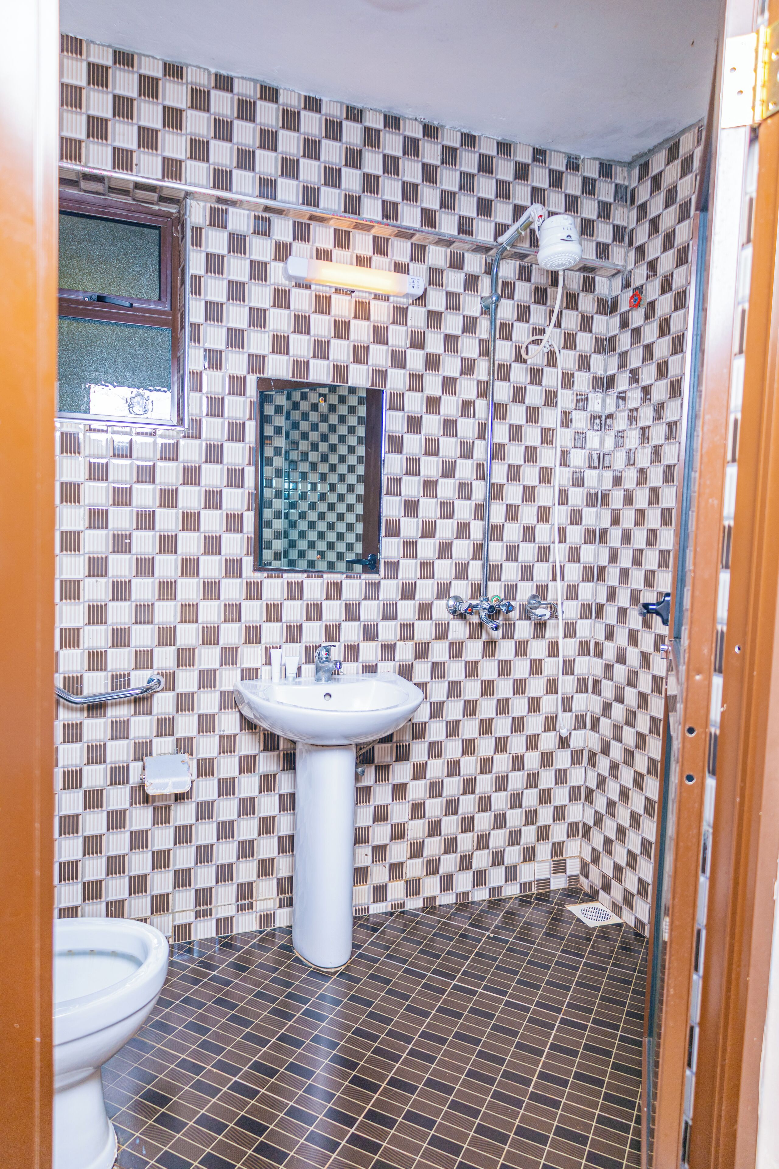 A bathroom with a checkered tile pattern, a sink, a mirror, and a shower.
