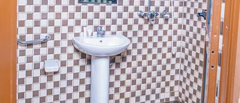 A bathroom with a checkered tile pattern, a sink, a mirror, and a shower.