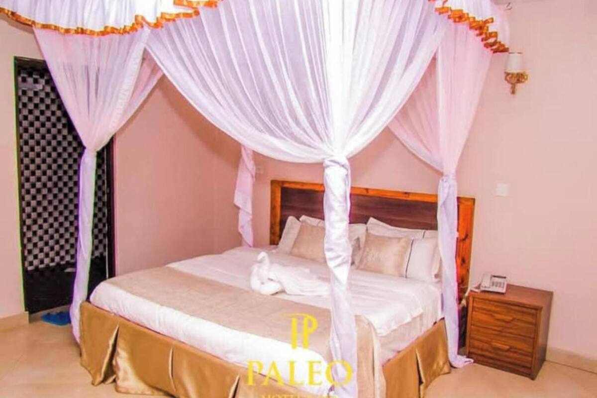 A bedroom with a canopy bed, a wooden nightstand, and a checkered door.