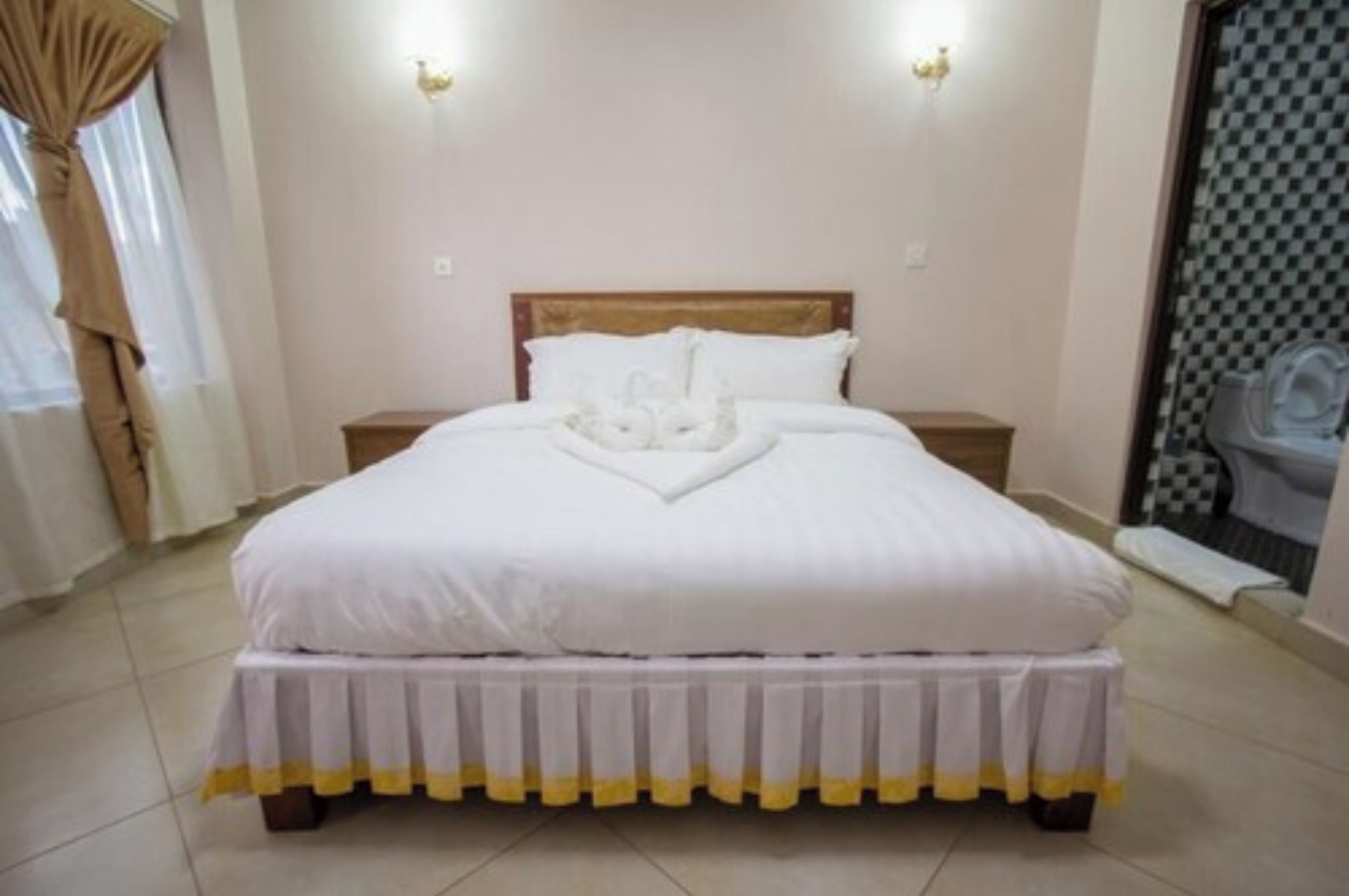 Una cama bien hecha con un edredón blanco y un arreglo decorativo de almohadas.