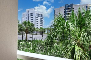 A modern building with a white facade, palm trees, and a clear blue sky.