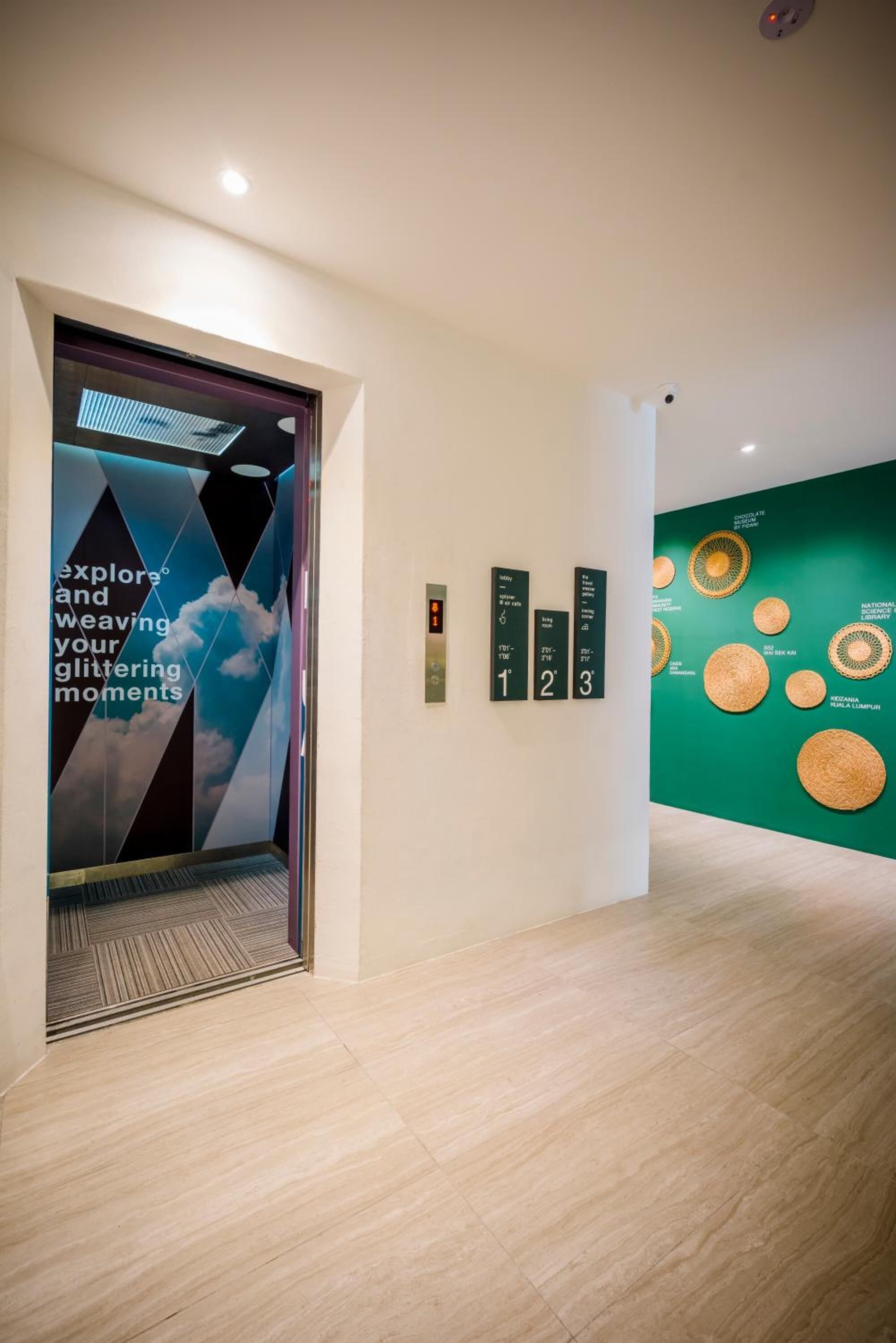 A modern elevator with a motivational poster, a digital display, and a green wall with woven baskets.